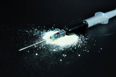 ilaç şırınga ve siyah yüzey üzerinde pişmiş eroin yakın çekim çekim