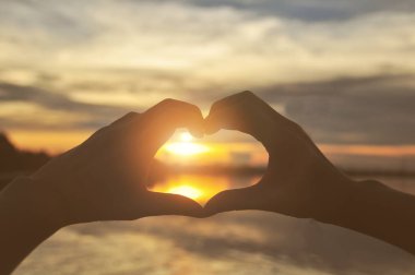 gün batımı ile kalp şekli oluşturan siluet eller