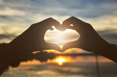 gün batımı ile kalp şekli oluşturan siluet eller