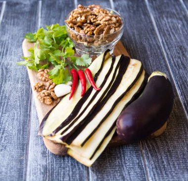 Patlıcan (bütün ve dilimlenmiş), fındık, biber ve otlar yemek için tahtada.