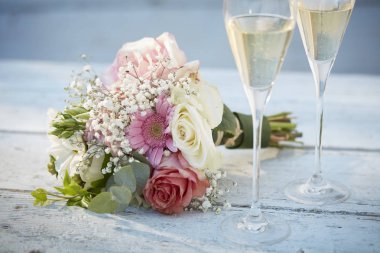 güzel düğün buket iki şampanya flüt yanında poz verdi. Bu nesneler bir güzel beyaz ahşap tahta üzerine yerleştirilir.