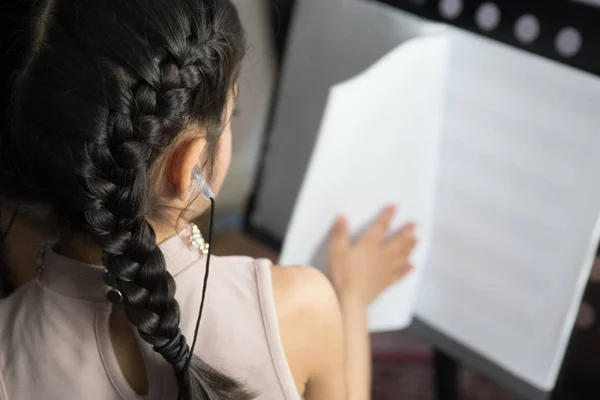 5 year old girl of British Indian origin practicing and playing the drums, reading music from notation - on a dark background with copy space.