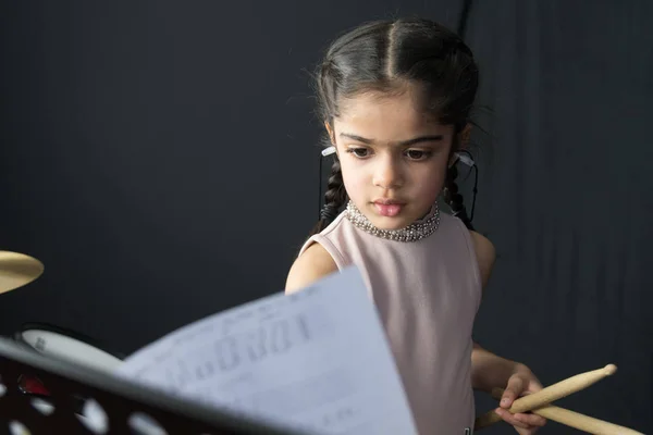 İngiliz Hint kökenli pratik ve davul çalmaya 5 yaşındaki kız yazıma - kopya alanı ile karanlık bir arka plan müzik okuma. 