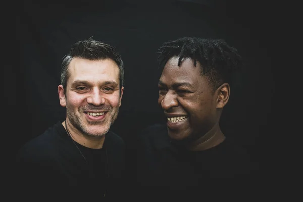 Jest sahne - fotoğraf Studio siyah bir arka plan önünde poz Interracial bir gay çift. 