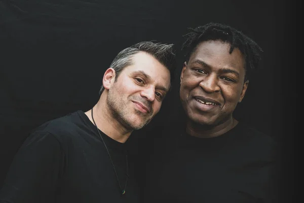 Jest sahne - fotoğraf Studio siyah bir arka plan önünde poz Interracial bir gay çift. 