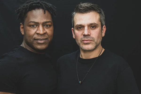 Jest sahne - fotoğraf Studio siyah bir arka plan önünde poz Interracial bir gay çift. 