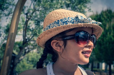 5 yaşında bir kız bir sunhat ve güneş gözlüğü tatilde iken bir tatil hotel dışında bir belboy Bagaj rafı üzerinde çalış. 