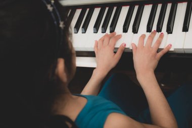 Okul çağındaki İngiliz kız evde piyano çalışıyor..
