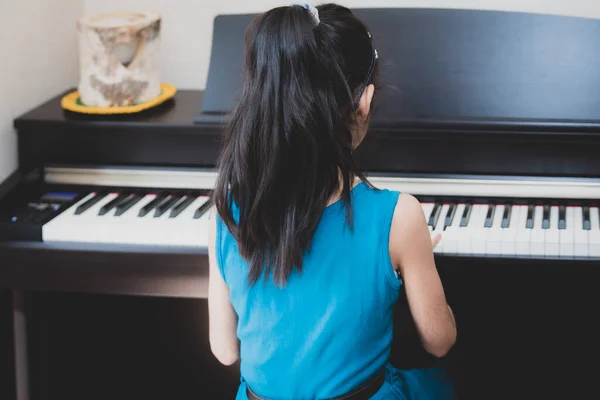 School age British Indian girl practices a piano at home.