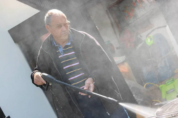 Senior Man Cleaning His Grill Using High Pressure Water — Stock Photo, Image