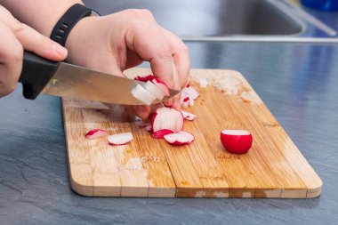 Kadınların elleri tahtada turp ve sebze kesiyor.