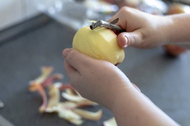 Yemek elma gri bir arka plan üzerinde peeling eller