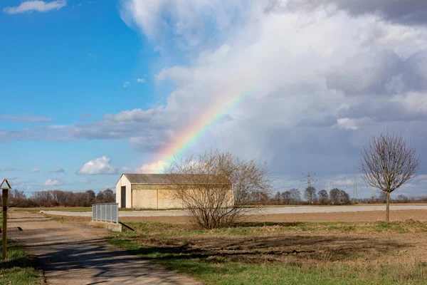 Arco iris en el cielo sobre el campo de primavera después de la tormenta — Foto de Stock