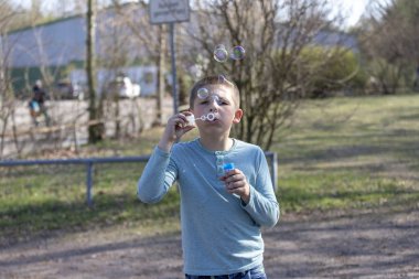 Küçük şirin çocuk parkta kabarcıklar üfleme