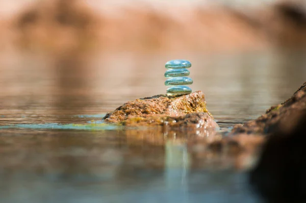 ZEN GLASS STONES STACKED BALANCING ON A ROCK