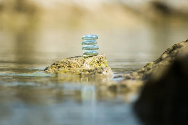 ZEN GLASS STONES STACKED BALANCING ON A ROCK