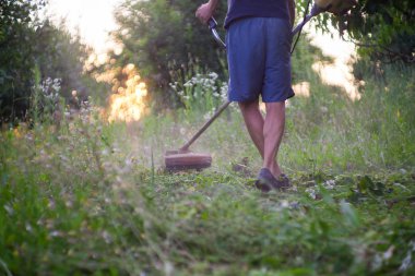 Bir budama makinesi ile yeşil çim biçen bir işçi