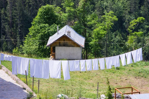 WOODEN CABIN IN THE FORREST WITH WHITE LAUNDRY INFRONT — Stock Photo, Image
