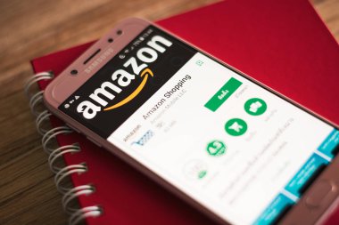 Phuket, Tayland - 23 Ağustos 2018: Amazon alışveriş uygulaması üstünde belgili tanımlık perde ahşap masa üstünde kırmızı defter ile Samsung Galaxy J7 pro smartphone başlattı.