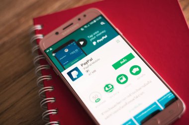 Phuket, Tayland - 23 Ağustos 2018: Paypal hareket eden kullanma üstünde belgili tanımlık perde ahşap masa üstünde kırmızı defter ile Samsung Galaxy J7 pro smartphone başlattı.