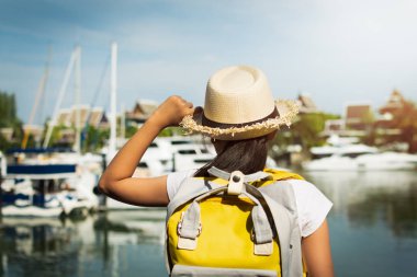Sırt çantası güneş ışığı, seyahat kavramı altında yat limanına bakan ile küçük bir kız arkasında görüntülemek.