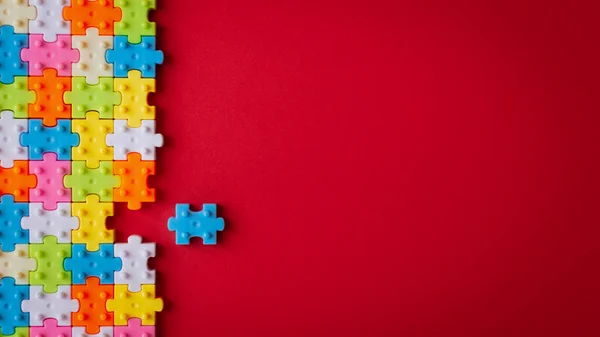 Colors plastic jigsaw puzzle on red paper background, Missing on Stock Image