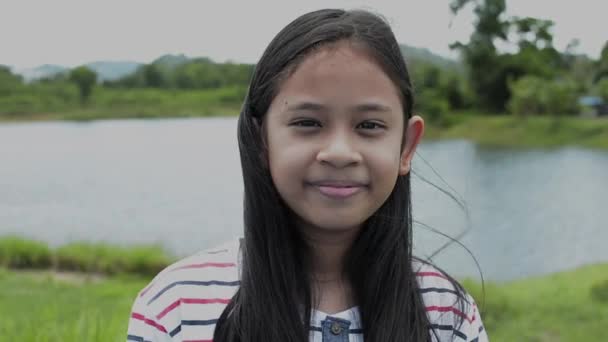 自然な盆地で楽しそうに微笑む長髪可愛い女の子のクローズアップポートレート — ストック動画