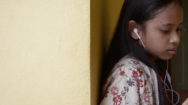 チノポルトガルスタイルの建物でイヤホンで携帯電話から音楽を聴く長い髪かわいい女の子 — ストック動画