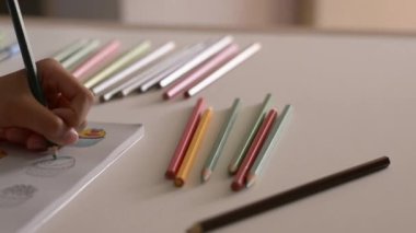 Masa, Sanat ve eğitim kavramı üzerinde renkli kalem ile bir kitapta küçük kız boyama resim El.