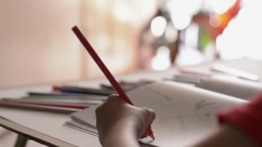 Masa, Sanat ve eğitim kavramı üzerinde renkli kalem ile bir kitapta küçük kız boyama resim El.