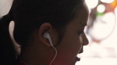 Küçük kız kulaklık ile cep telefonundan müzik dinlerken ve evde oturan.