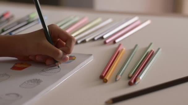 Ruka z malé holčičky barvuje obrázek v knize s barevnou tužkou na psacím stole, Art a vzděláním.