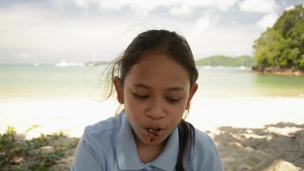 Mała Dziewczynka Jedzenia Pyszne Grillowane Skrzydło Kurczaka Pod Cieniu Plaży — Wideo stockowe