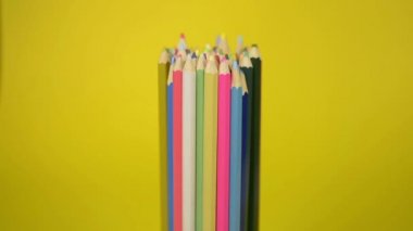 Birlikte bağlanmış renkli kalemler sarı arka planda, birlik ve organizasyon konseptinin işbirliği üzerinde düzensiz düşme vardır.