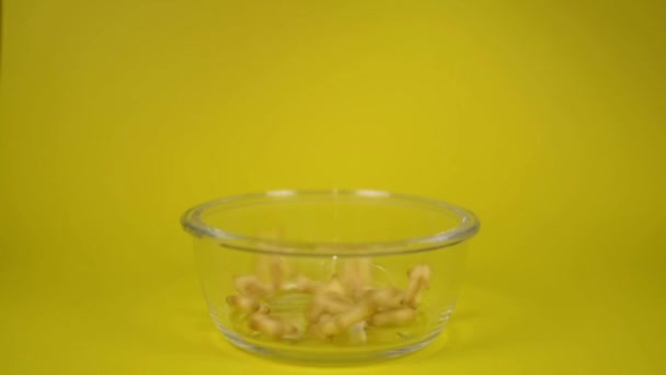 饼干海鲜形状倒入透明碗隔离在黄色背景 — 图库视频影像