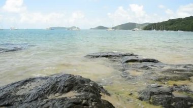 Ao Yon Beach Sahil şeridinde sahne, dalgalar düşük açı görünümünde kayalar üzerinde yıkanmış, Phuket bulutlu mavi gökyüzü altında Yatlar ile Andaman Denizi, Tayland.