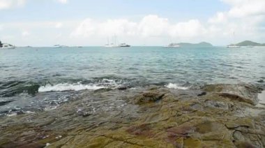 Ao Yon Beach Sahil şeridinde sahne, dalgalar düşük açı görünümünde kayalar üzerinde yıkanmış, Phuket bulutlu mavi gökyüzü altında Yatlar ile Andaman Denizi, Tayland.