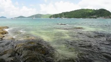 Ao Yon Beach Sahil şeridinde sahne, dalgalar düşük açı görünümünde kayalar üzerinde yıkanmış, Phuket bulutlu mavi gökyüzü altında Yatlar ile Andaman Denizi, Tayland.