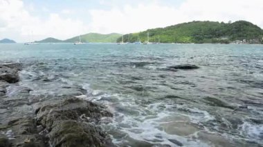 Ao Yon Beach Sahil şeridinde sahne, dalgalar düşük açı görünümünde kayalar üzerinde yıkanmış, Phuket bulutlu mavi gökyüzü altında Yatlar ile Andaman Denizi, Tayland.