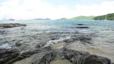 Ao Yon Beach Sahil şeridinde sahne, dalgalar düşük açı görünümünde kayalar üzerinde yıkanmış, Phuket bulutlu mavi gökyüzü altında Yatlar ile Andaman Denizi, Tayland.