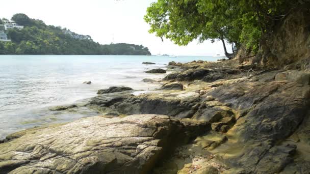 アオヨンビーチの海岸線の風景 波は低角の眺めで岩に洗い流され プーケット タイの曇り青い空の下でヨットとアンダマン海 — ストック動画