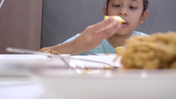 ランチタイムにテーブルの上に食べ物を食べるかわいい女の子の肖像画 低角度の視点で撮影 — ストック動画