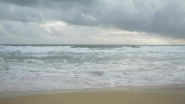 Karon plajı, Phuket, Tayland gökyüzünde bir deniz kıyısı ve yağmur bulutları üzerinde kırma dalgaları tarafından oluşturulan köpük ile tropikal kumlu plaj Manzarası.