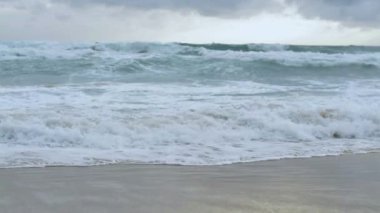Karon plajında yağmur bulutları gökyüzü altında plaj sıçrayan büyük sörf dalgası ile deniz suyu yavaş hareket, Phuket, Tayland.