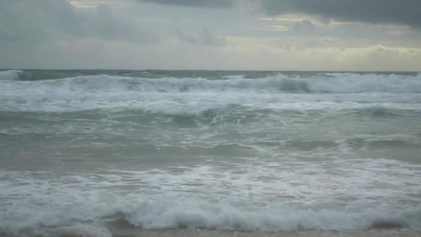 Paysage de plage de sable tropical avec de la mousse formée par des vagues se brisant sur un rivage et des nuages de pluie dans le ciel à la plage de karon, Phuket, Thaïlande .