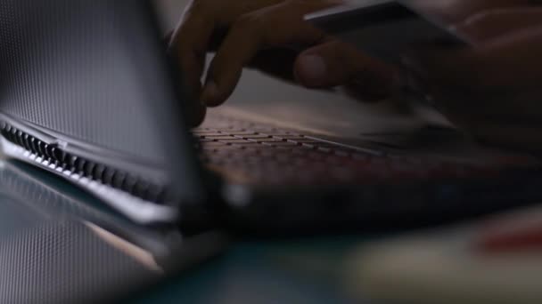 Hands of a man holding a credit card and typing laptop keyboard for online payment on the desk at home during COVID-19 outbreak situation. Travail à domicile.