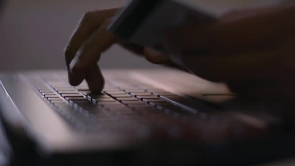 クレジットカードを持っている男性の手とCovid 19発生状況中に自宅で机の上にオンライン決済のためのラップトップキーボードを入力します 家からの仕事 — ストック動画