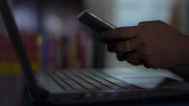 İletişim kurmak için akıllı telefon kullanan ve geceleri çalışma masasında sosyal hayatla sohbet eden bir kadının elleri..