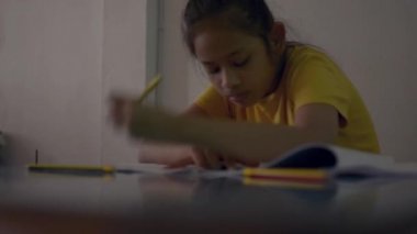 Gündelik elbiseli tatlı kız ödevlerini masa başında yapıyor, eğitim konsepti..