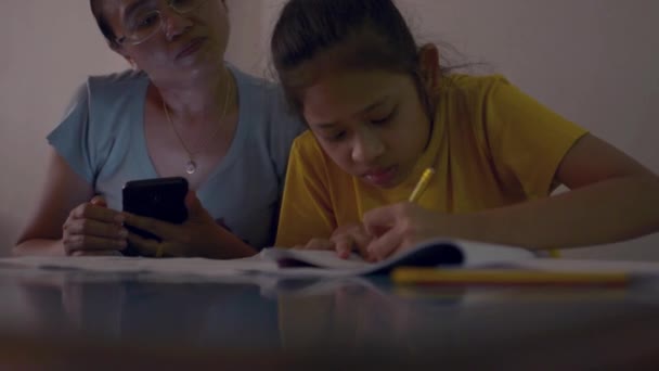 Mère Utilise Téléphone Intelligent Enseigne Les Devoirs Fille Sur Bureau — Video